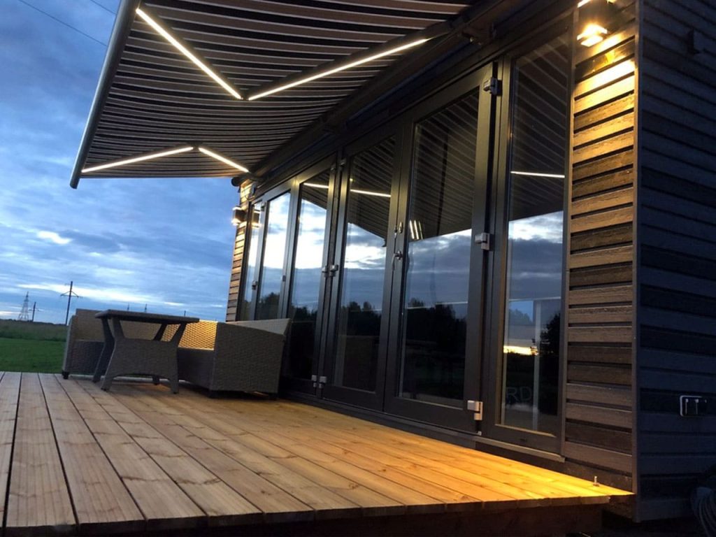 Markis med LED-belysning på trädäck vid kvällstid