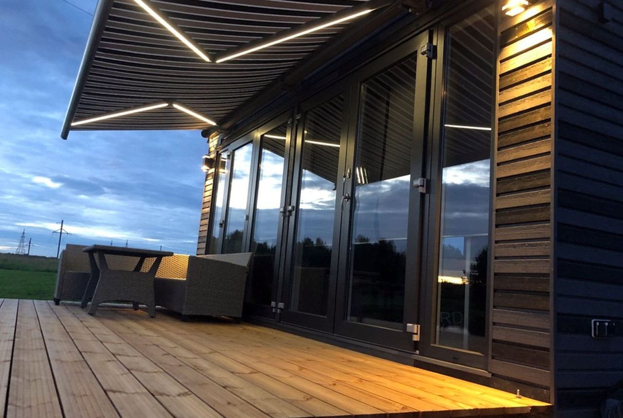 Markis med LED-belysning på träterrass vid skymning