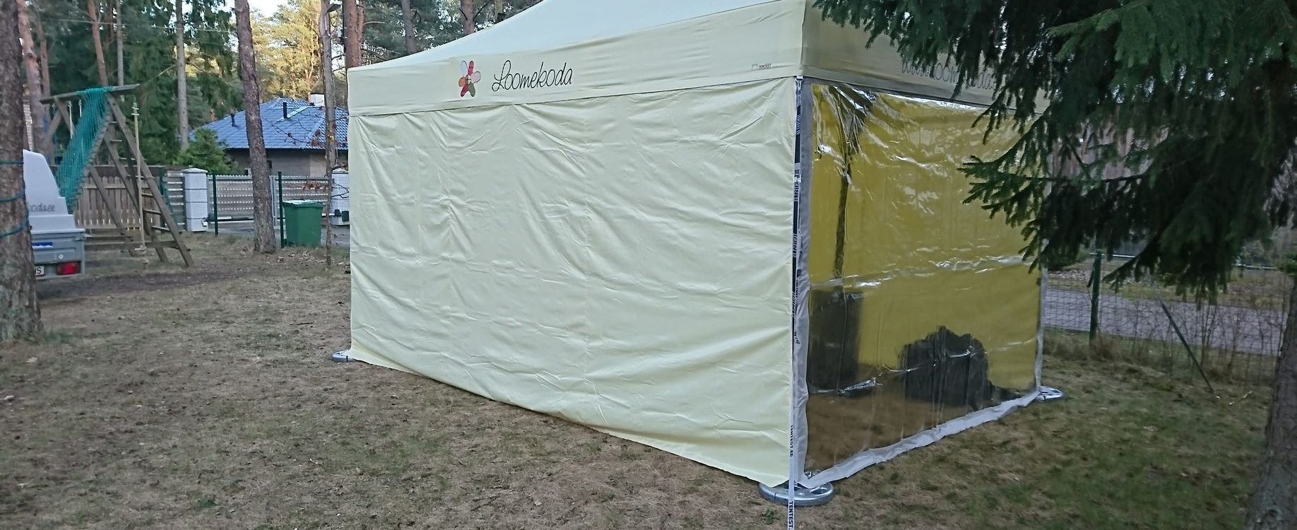 Lomakoda tält valkoisella katolla ja keltaisilla sivuseinillä metsän keskellä leirintäalueella
